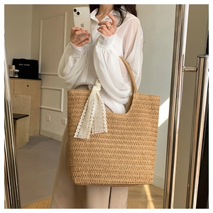 Close-up of handwoven straw tote bag featuring detailed khaki texture and lace ribbon bow