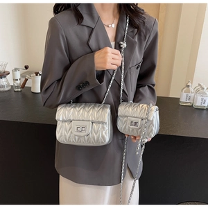 Detail of silver quilted chain bags showing metallic texture and rotary lock on model