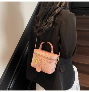 Detailed back view of pink embossed crossbody box bag with golden zipper on black blazer