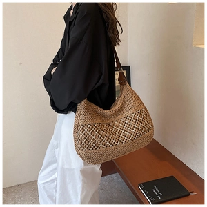 Detail of hollow-out woven straw tote bag with brown leather strap and mesh texture