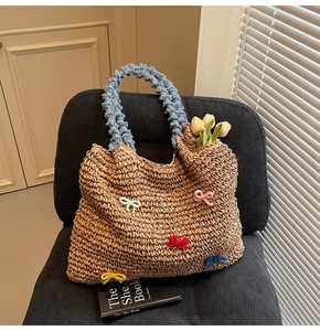 Close-up of straw tote bag with colorful knitted bows and soft blue plush handles