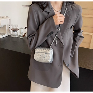 Silver metallic quilted chain bag styled with a grey blazer in a cafe setting
