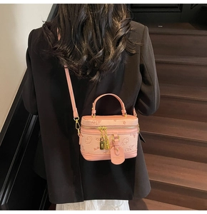 Close-up of pink rectangular bag with embossed animal pattern and golden padlock