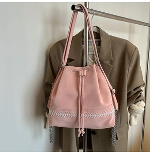 Dettaglio borsa a secchiello rosa con chiusura a coulisse e ricamo a freccia bianca