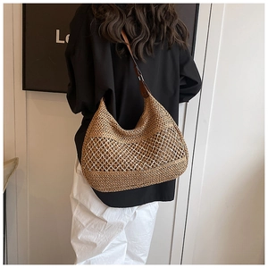 Detail of woven straw hobo bag with hollow texture and brown leather shoulder strap