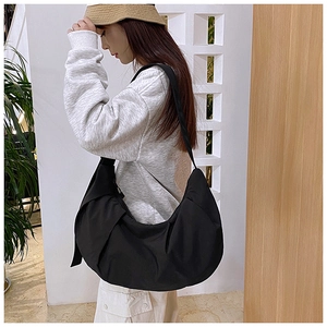 Detailed side view of black crescent crossbody bag showing its large capacity and soft drapes