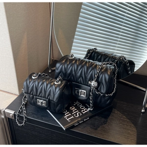 Detail of black quilted leather shoulder bags in two sizes with silver chain and twist lock