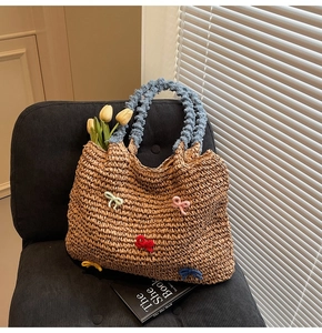 Detail of straw woven tote bag with colorful 3D bow accents and light blue fluffy handle