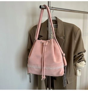 Dettaglio borsa a secchiello rosa con coulisse, ricami ondulati bianchi e catene metalliche