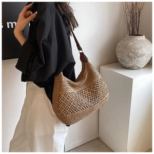 Close-up of handmade hollow woven straw shoulder bag with elegant brown strap and metal detail