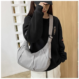Detail of grey dumpling messenger bag showing textured nylon fabric and adjustable strap