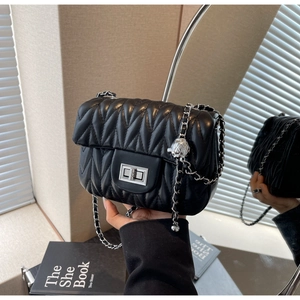 Detail of black quilted chain bag with silver square lock and metallic ball adjuster