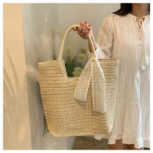 Detail of woven straw tote bag with textured horizontal weave and lace ribbon handle