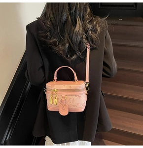 Pink lychee leather crossbody bag with embossed dog pattern on a model in black blazer