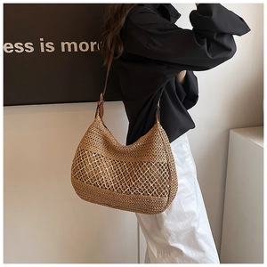 French style large woven straw shoulder bag with brown leather strap in a minimal room