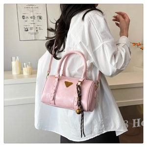 Detail of pink Boston handbag with golden triangle plaque and striped bell charm