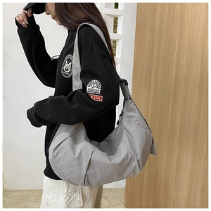Detailed side view of a gray hobo bag featuring natural pleated fabric and wide shoulder strap