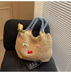 Detail of straw tote bag with colorful knitted bows and blue textured handles