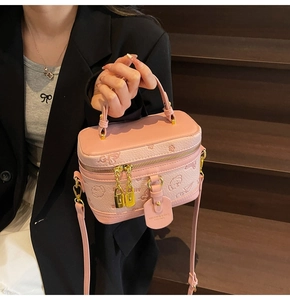 Pink cylinder handbag with cartoon animal embossing held by model on wooden stairs