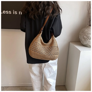 Detail of straw woven tote with white crochet lace and brown leather strap on model back