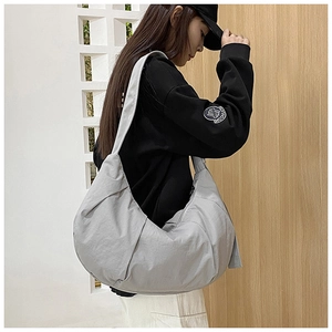 Detailed side view of grey oversized nylon dumpling bag showing pleated texture and wide strap