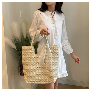 Close-up of a handmade woven straw tote bag featuring decorative lace ribbon and handle details