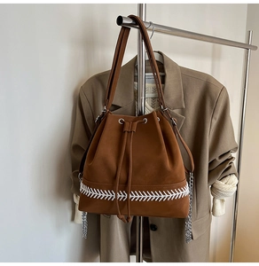 Dettaglio di una borsa a secchiello marrone scuro con coulisse e cuciture bianche stile baseball