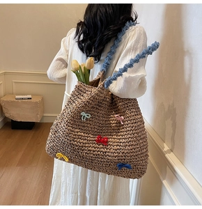Detail of straw woven tote with colorful plush bows and blue fuzzy shoulder strap