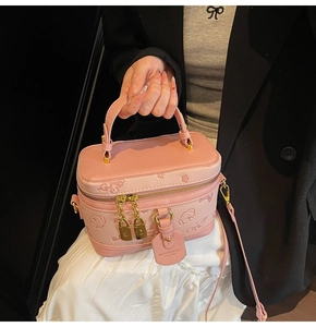 Detail of pink vanity box bag with embossed floral pattern and gold padlock zipper