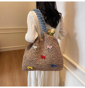 Detail of straw tote bag with colorful knitted bows and blue ruffled shoulder straps