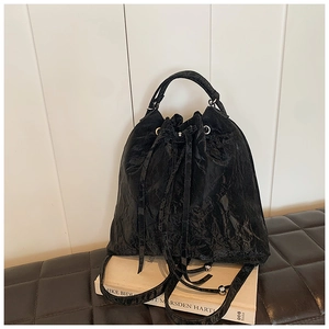 Detail of black drawstring bucket bag showing natural wrinkled leather texture and handle