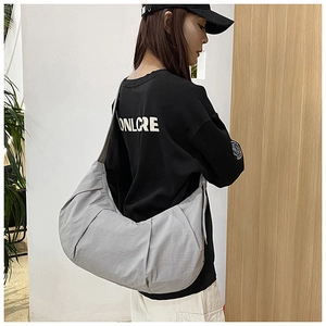 Gray nylon crossbody dumpling bag with pleated design worn by model for daily commute