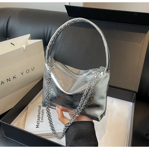 Detailed macro view of metallic silver bucket bag with chain strap in a gift box