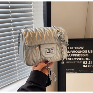 Close-up of wavy quilted silver chain bag with a metallic twist lock and chic design