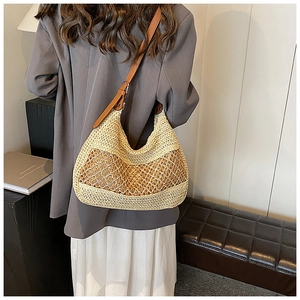 Detail of hollow-out woven straw shoulder bag with brown leather strap and mesh texture