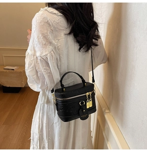 Detail of black pebbled leather box bag with embossed floral patterns and gold hardware