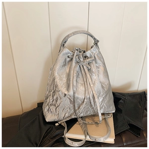 Detailed view of silver metallic drawstring bucket bag with pleated texture and top handle