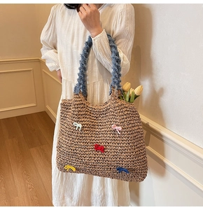 Detail of straw woven tote bag featuring colorful bow knots and blue textured handles