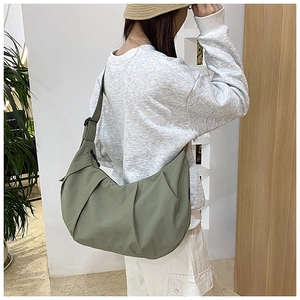 Detail view of olive green crescent bag with adjustable strap and textured nylon surface