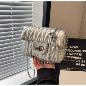 Detail of silver metallic quilted crossbody bag with stylish chain strap and twist lock