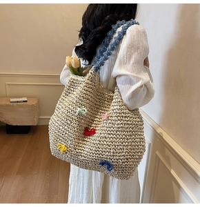 Detail view of woven tote with colorful knit bows and textured blue shoulder strap