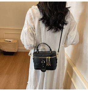 Detail of elegant black embossed crossbody box bag with gold zipper on a model