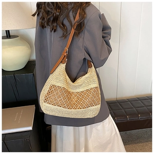 Detail of bohemian straw shoulder bag with adjustable brown leather strap on a model