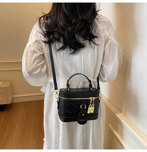 Detail view of stylish black embossed leather crossbody bag with elegant gold hardware