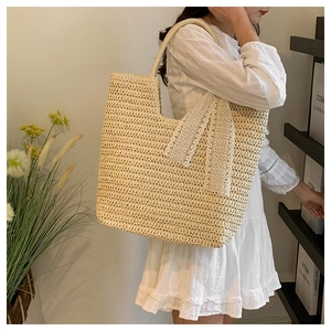 Detailed texture of straw tote bag featuring white lace ribbon bow and woven pattern