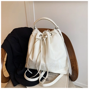 White drawstring bucket bag with marble texture placed on a wooden chair with a blazer