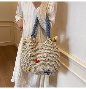 Detail of woven straw tote bag with colorful bows and blue plush shoulder handles