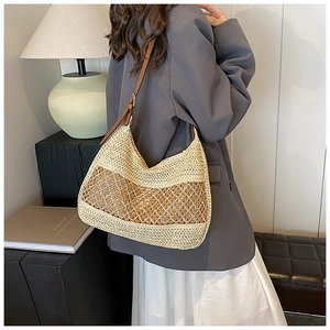 Detail of woven straw shoulder bag featuring a brown leather strap and texture