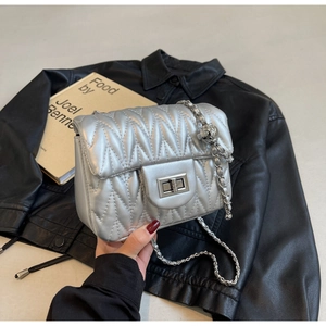 Close-up of silver quilted chain bag with sleek metal turn-lock and metallic finish