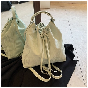 Detail of mint green drawstring bucket bag with pleated texture and bow decoration